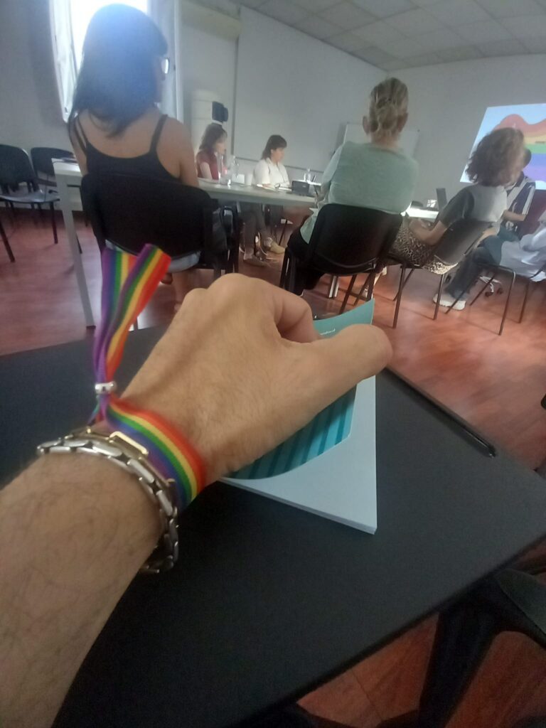 Foto d'una persona amb polsera LGTBI+ prenent notes en la formació