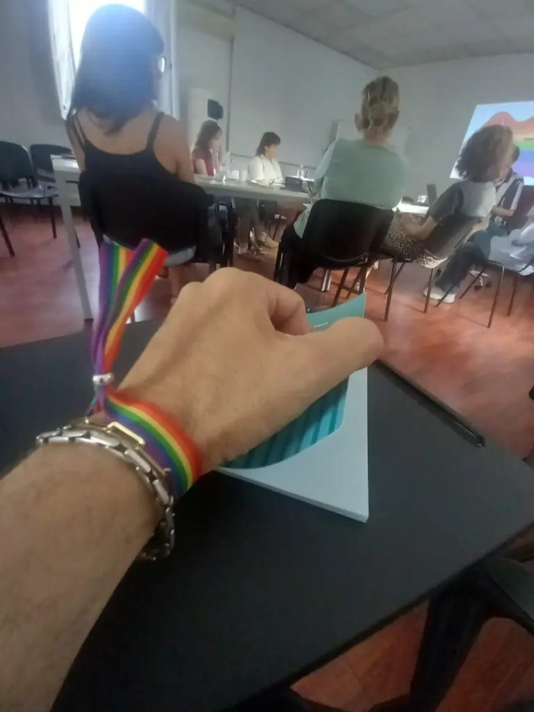 Foto de una persona con pulsera LGTBIQ+ tomando notas en la formación