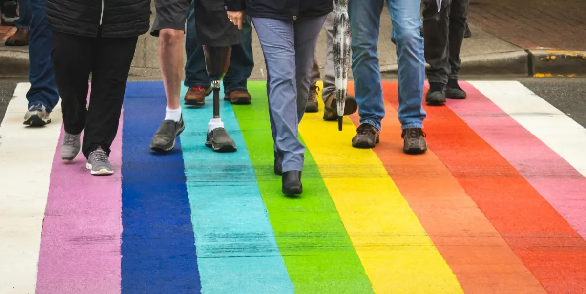 Hombres cruzando una calle pintada de colores arcoiris
